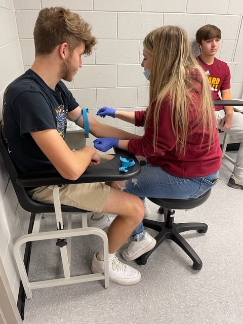 Phlebotomy Student practicing an arm IV. 